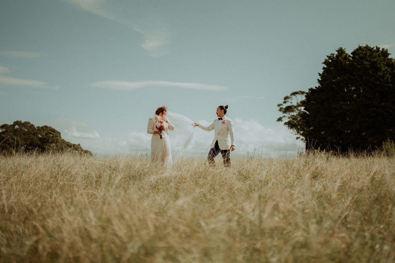 A bride and groom walking toward each other across a wide golden field