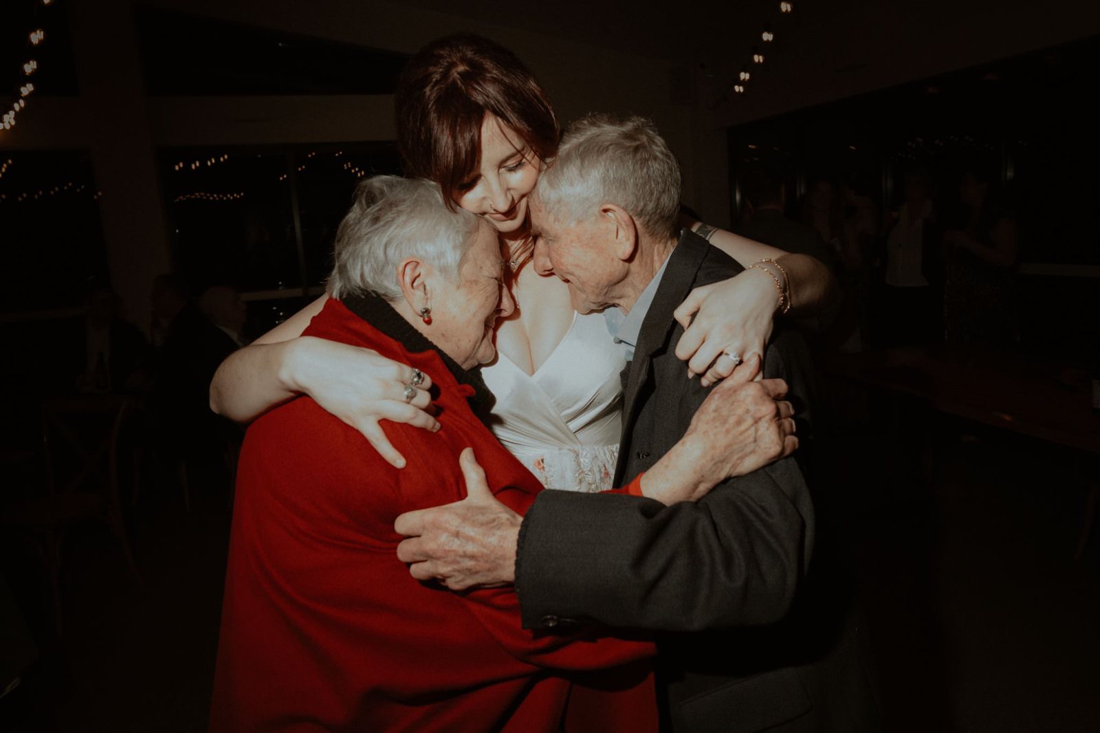 A bride wrapping her arms around an elderly couple on the dance floor